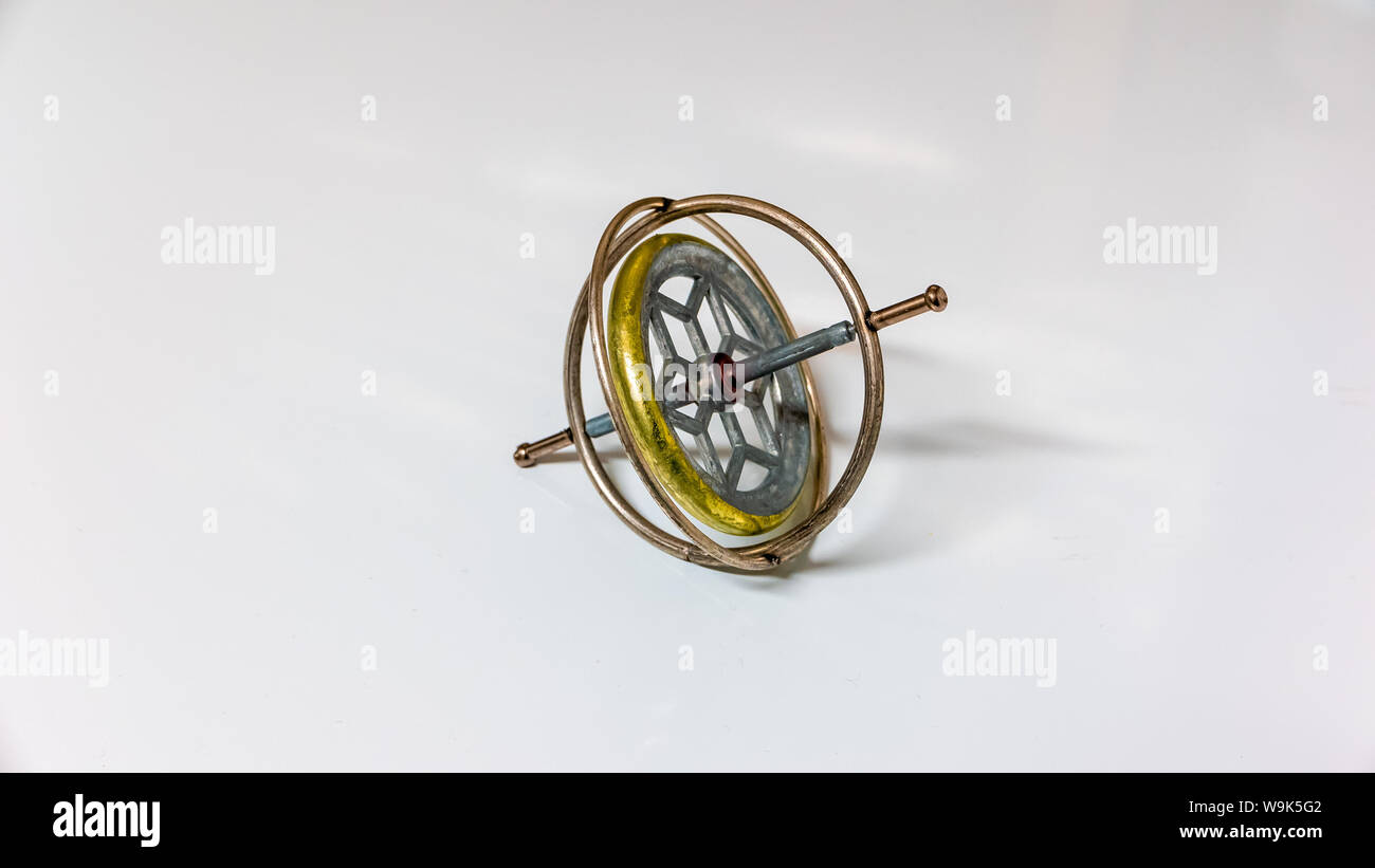 Un giroscopio de juguete de metal aislado sobre un fondo blanco. Foto de stock