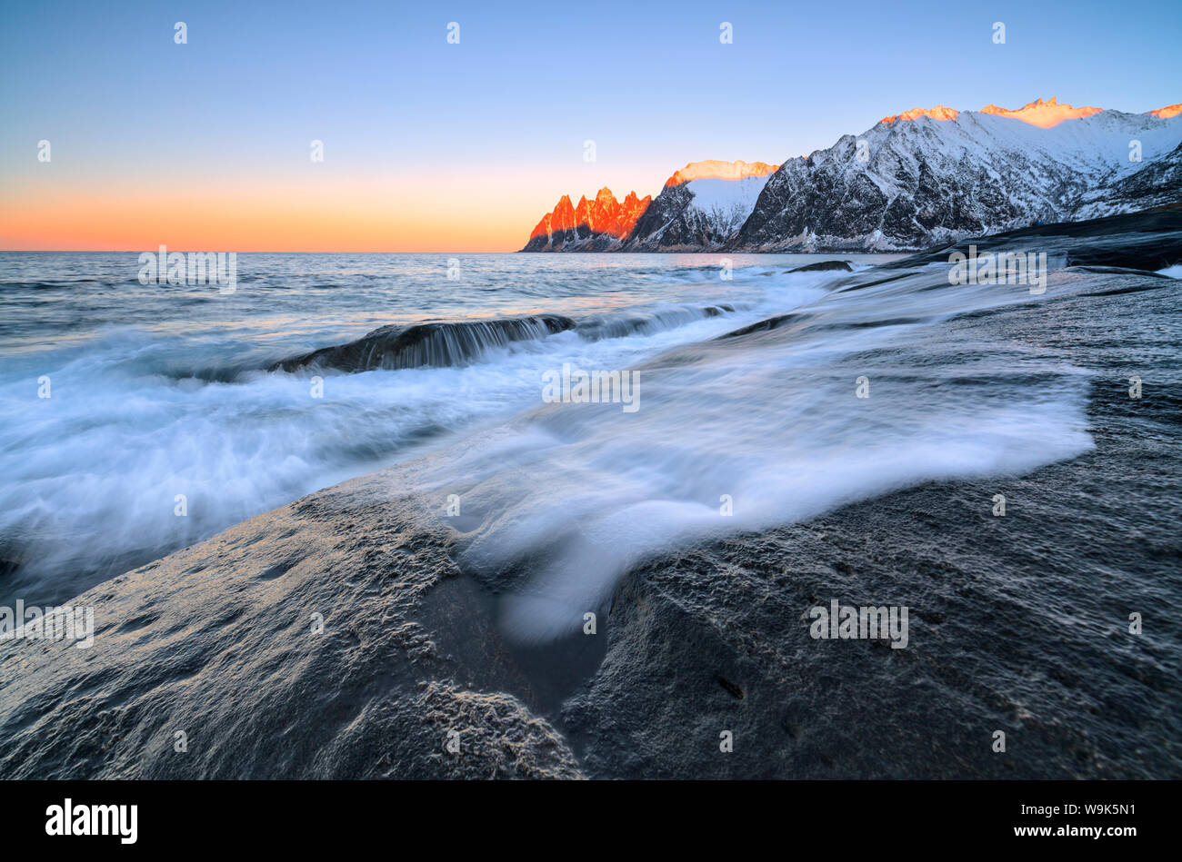 Las olas del mar helado estrellándose en los acantilados rocosos al amanecer Tungeneset, Senja, condado de Troms, Ártico, en Noruega, Escandinavia, Europa Foto de stock