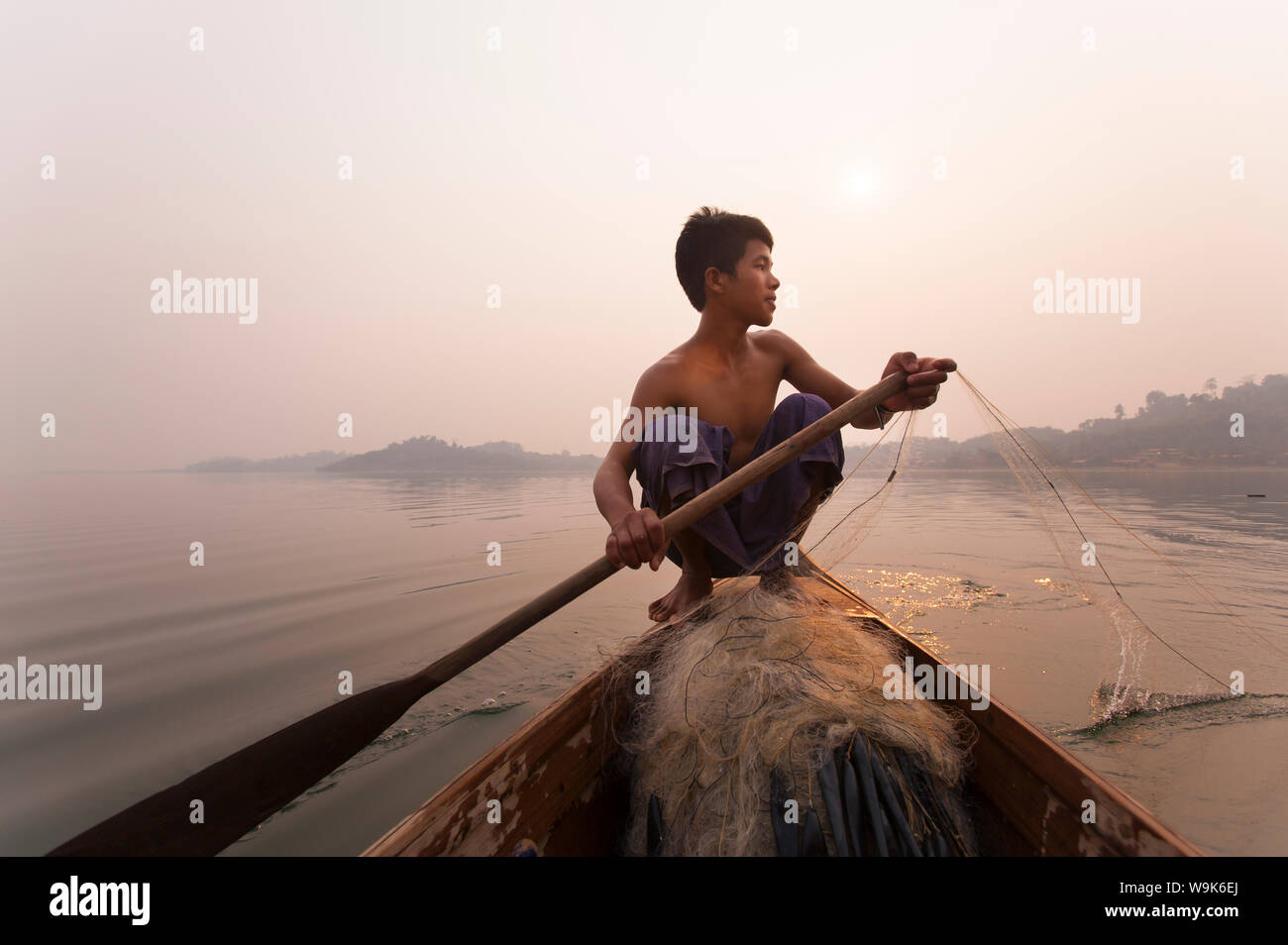 Un hombre joven saca en sus redes al final del día en el lago Indawgyi, Estado de Kachin, en Myanmar (Birmania), Asia Foto de stock