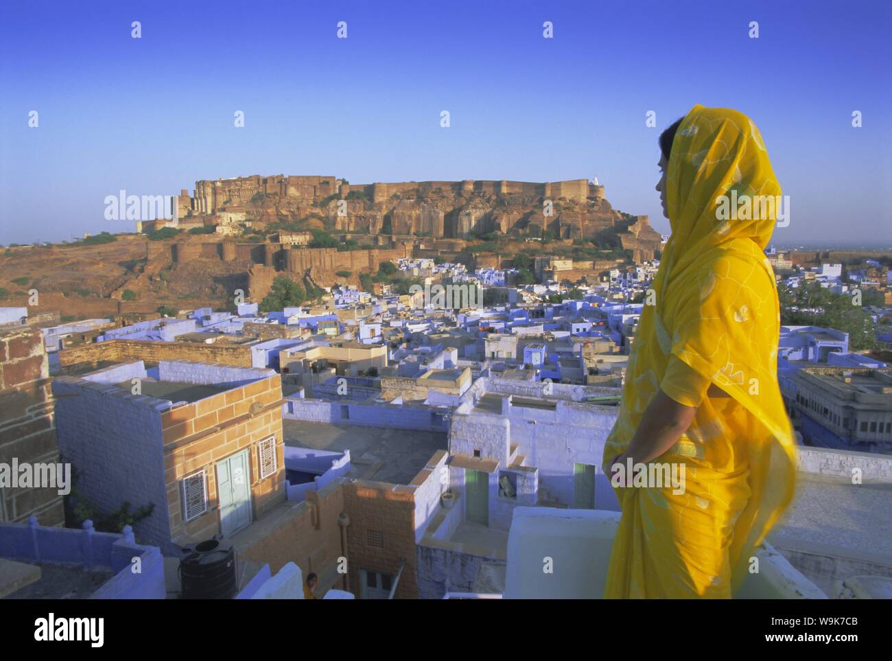 Una mujer con un sari amarillo mirando a través de la 'ciudad azul' y fort, Jodhpur, Estado de Rajasthan, India, Asia Foto de stock