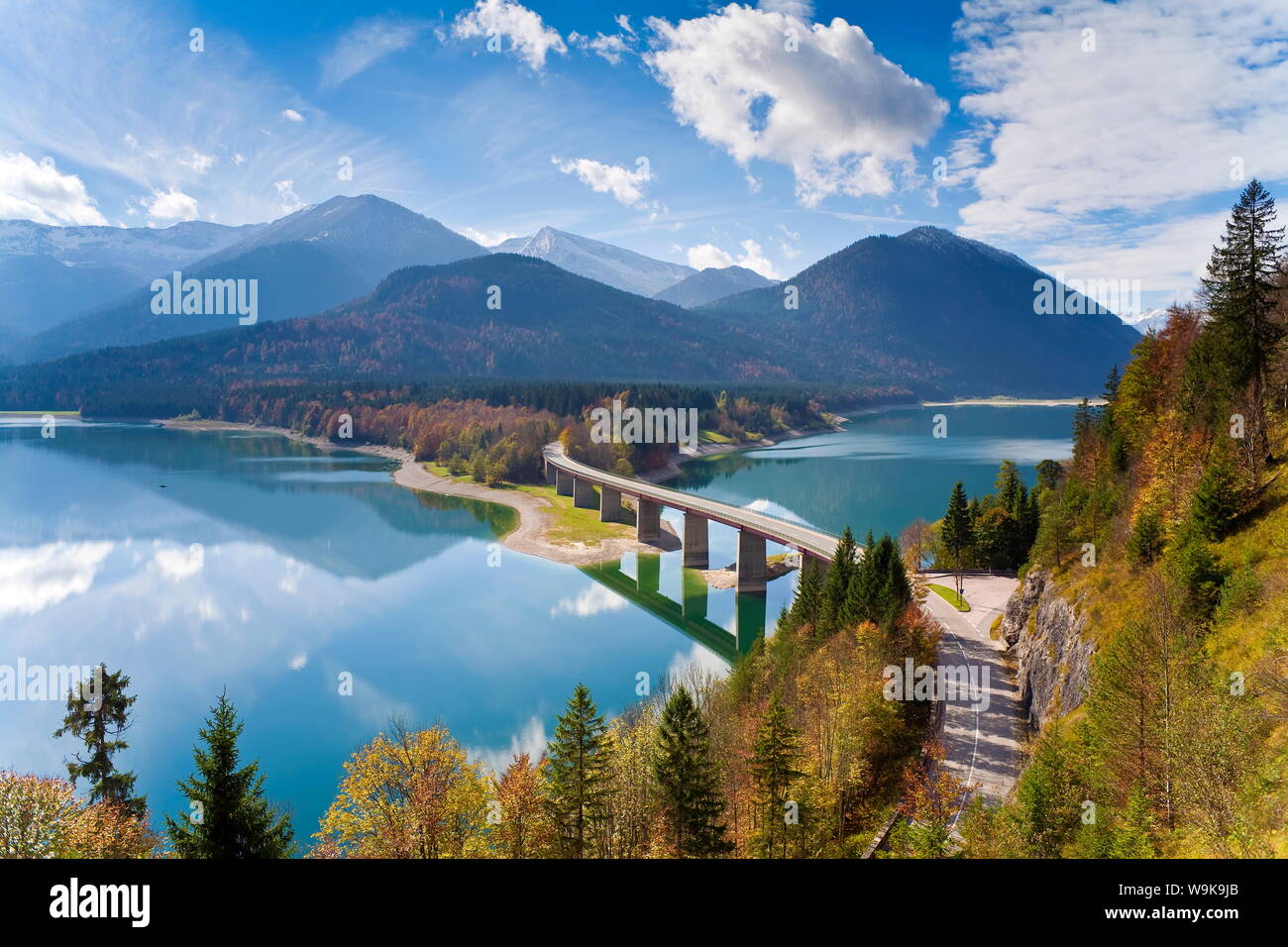 Reflexiones de un puente de carretera sobre el lago Sylvenstein, con montañas de fondo, Baviera, Alemania, Europa Foto de stock