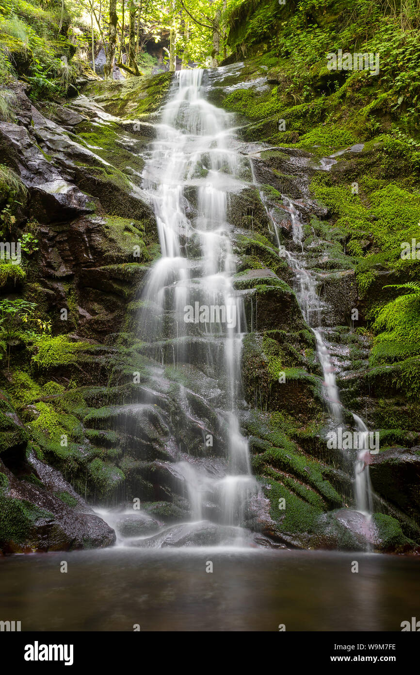 Impresionantes paisajes de montaña cascada en cascada hacia el precipicio  rocoso cubierto por musgo verde vivo, colorido y parches de sol golpeando  las rocas Fotografía de stock - Alamy