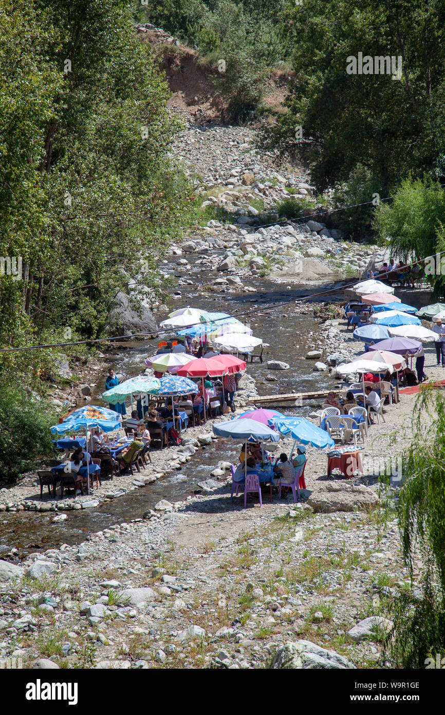La gente se sienta en los restaurantes en el río, en ITS Fadma, Valle de Ourika en las montañas del Atlas, Marruecos Foto de stock