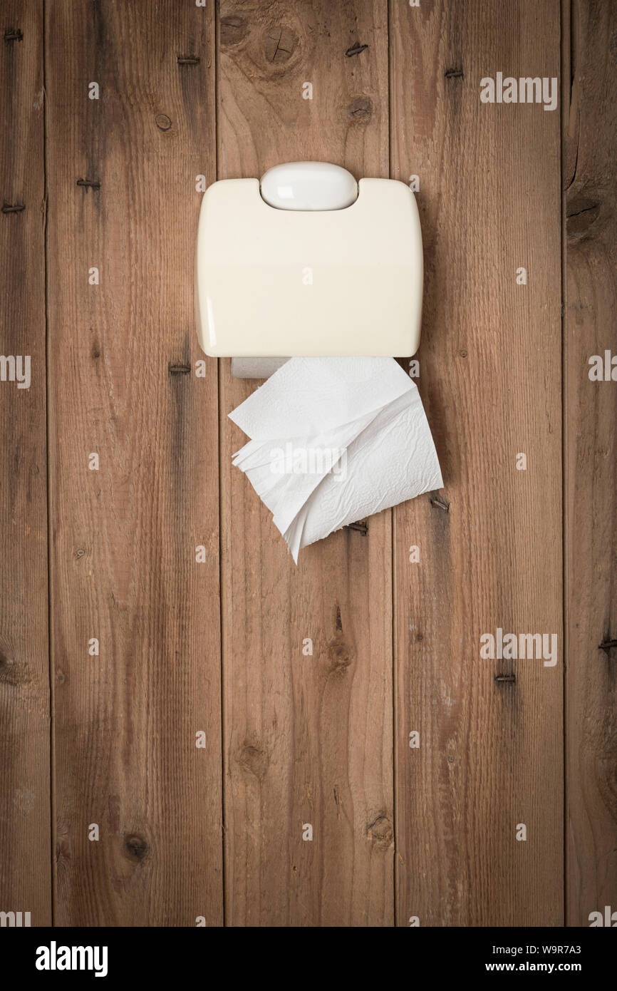 Última hoja de papel higiénico en el portarrollos de pared de madera de  letrina Fotografía de stock - Alamy