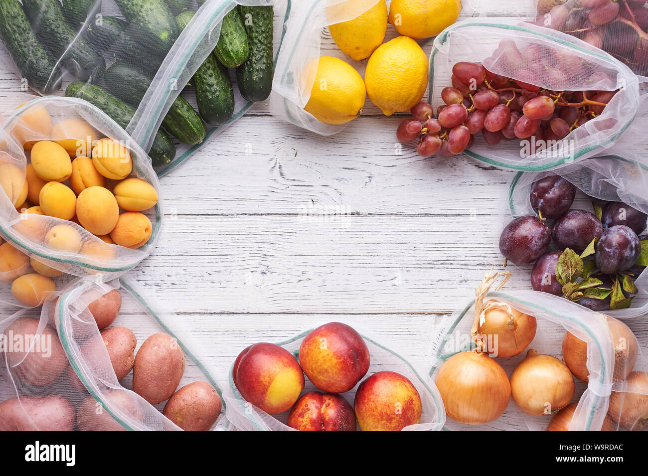 Bastidor de frutas y verduras en bolsas ecológicas reutilizables en fondo  blanco de madera. Bolsas de reciclado en lugar de bolsas de plástico. Libre  de plástico. Vista superior de laicos plana Fotografía