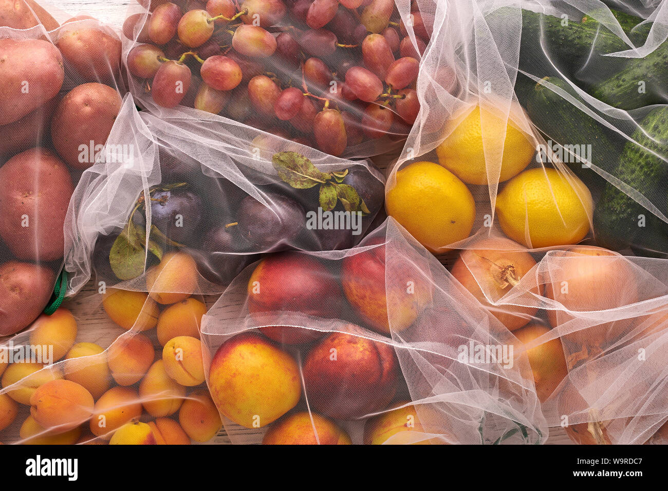 Frutas y verduras en bolsas ecológicas reutilizables en fondo blanco de  madera. Bolsas de reciclado en lugar de bolsas de plástico. Libre de  plástico. Vista superior de laicos plana Fotografía de stock -