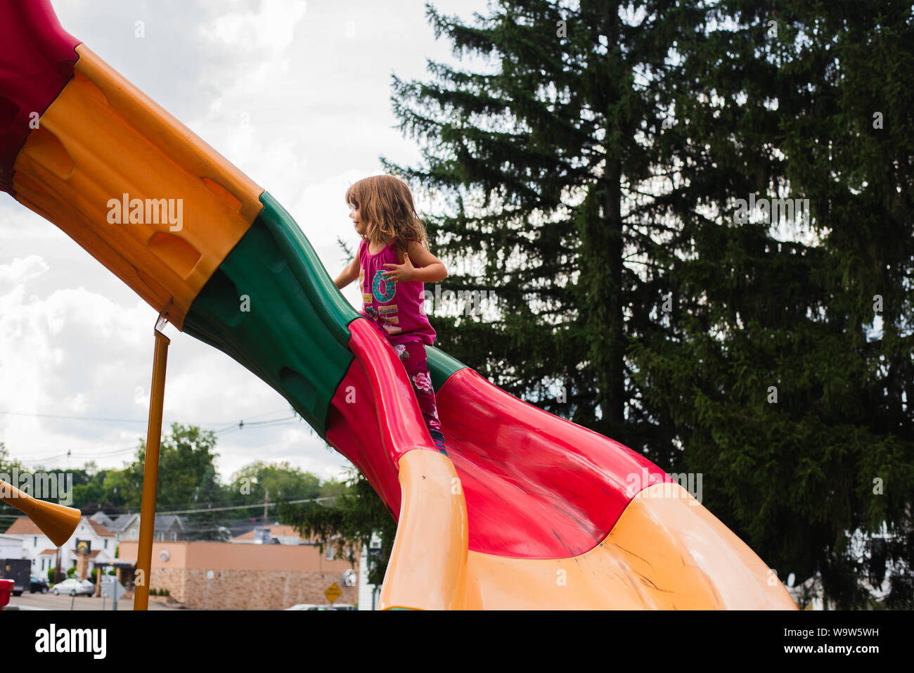 Una niña de 4 años de antigüedad en una colorida diapositiva en un parque. Foto de stock