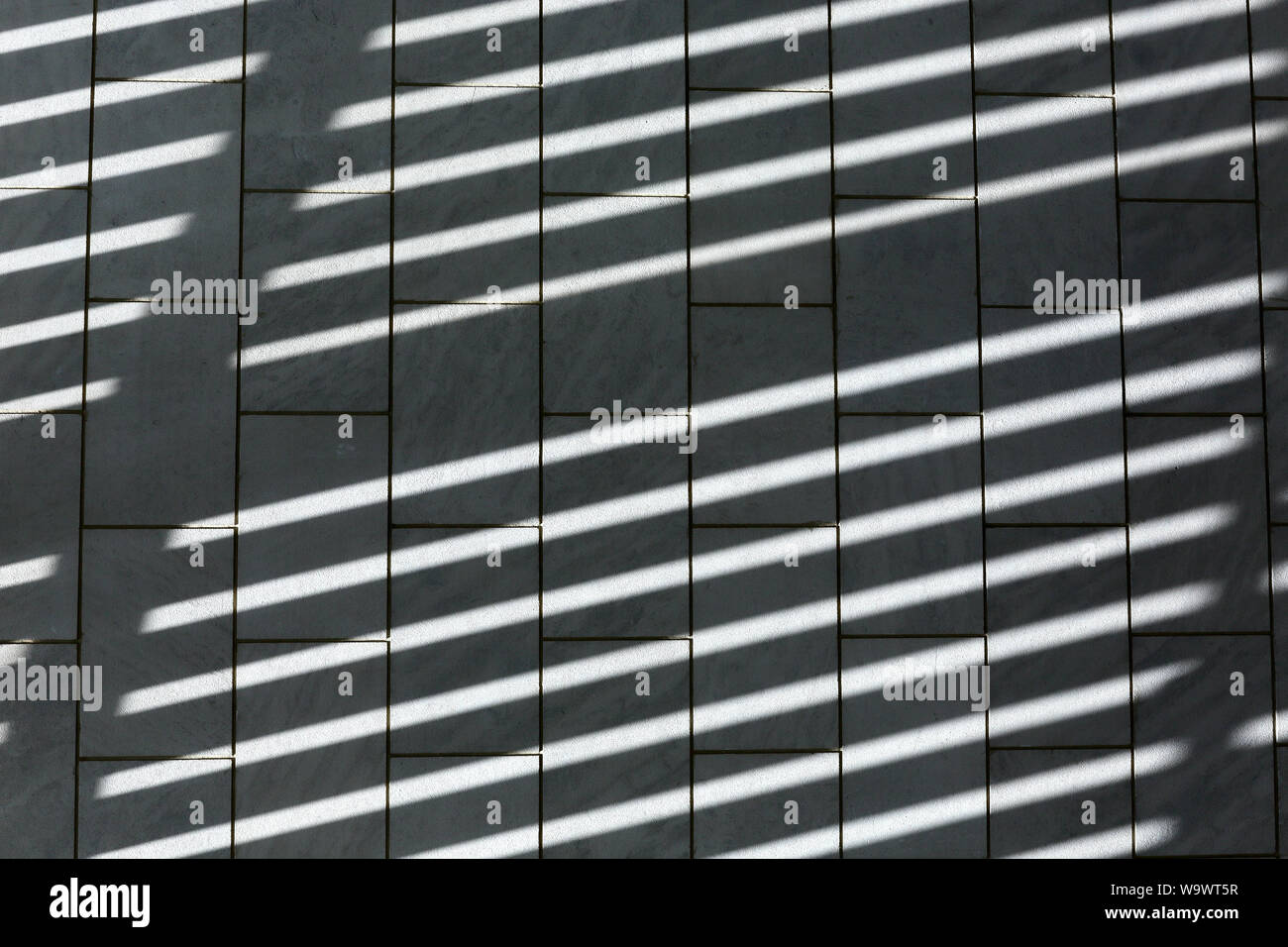 Patrón de sombras sobre un piso de baldosas con paredes verticales y las líneas angulares Foto de stock