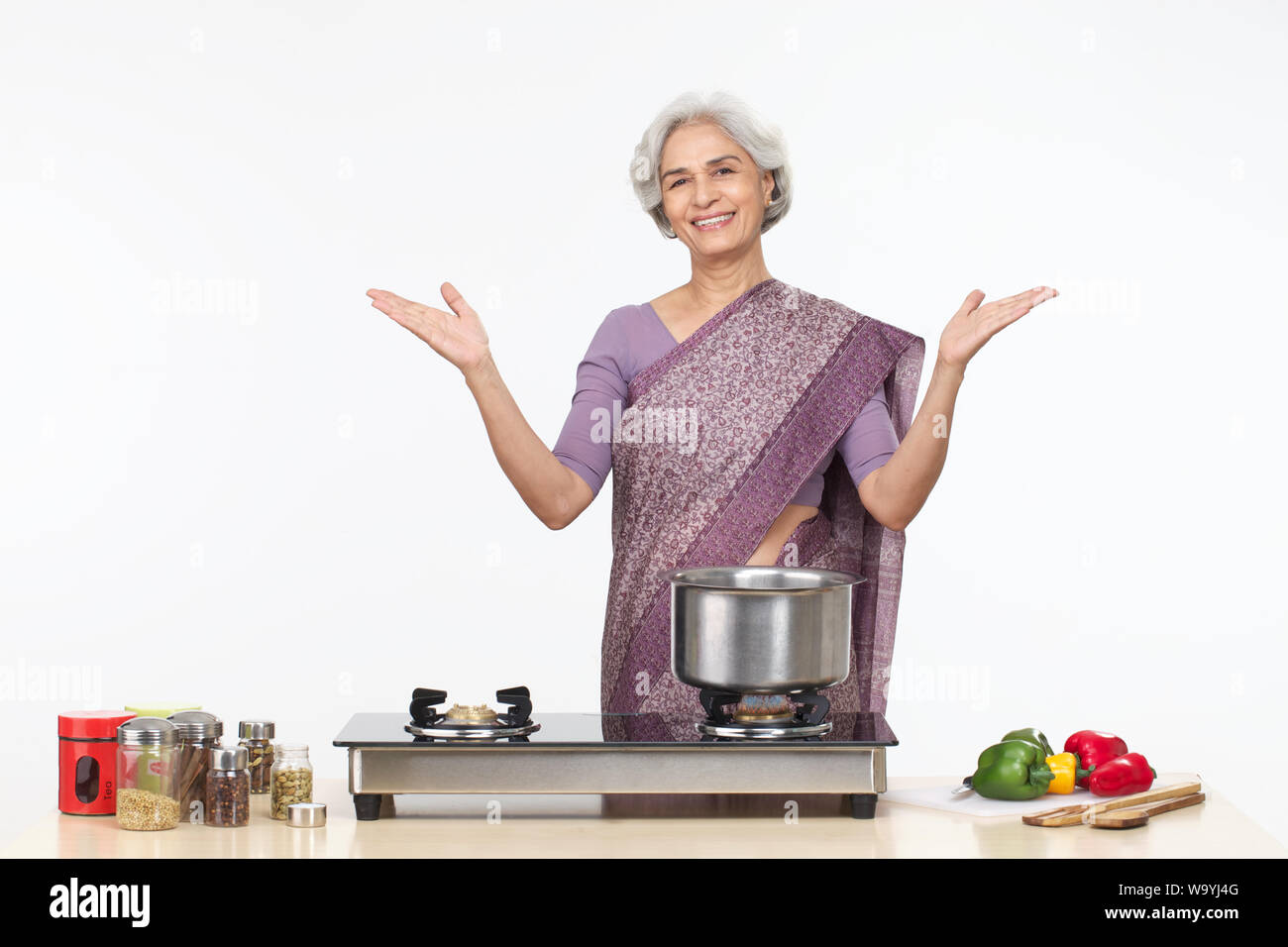Mujer mayor gestando en el mostrador de la cocina y sonriendo Foto de stock