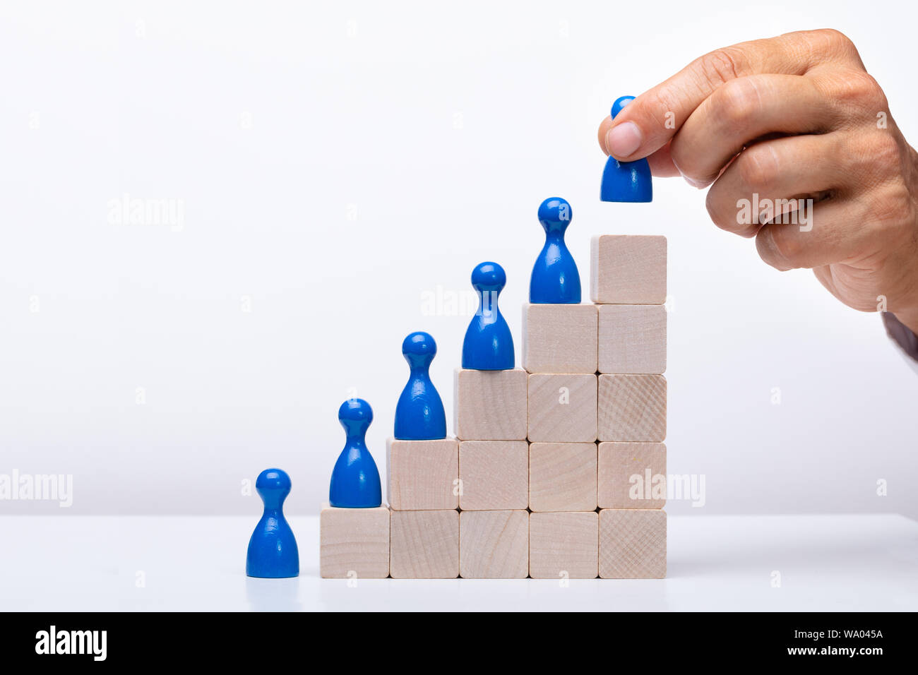 Empresario poniendo Azul Figura Humana en la parte superior del bloque de madera Foto de stock