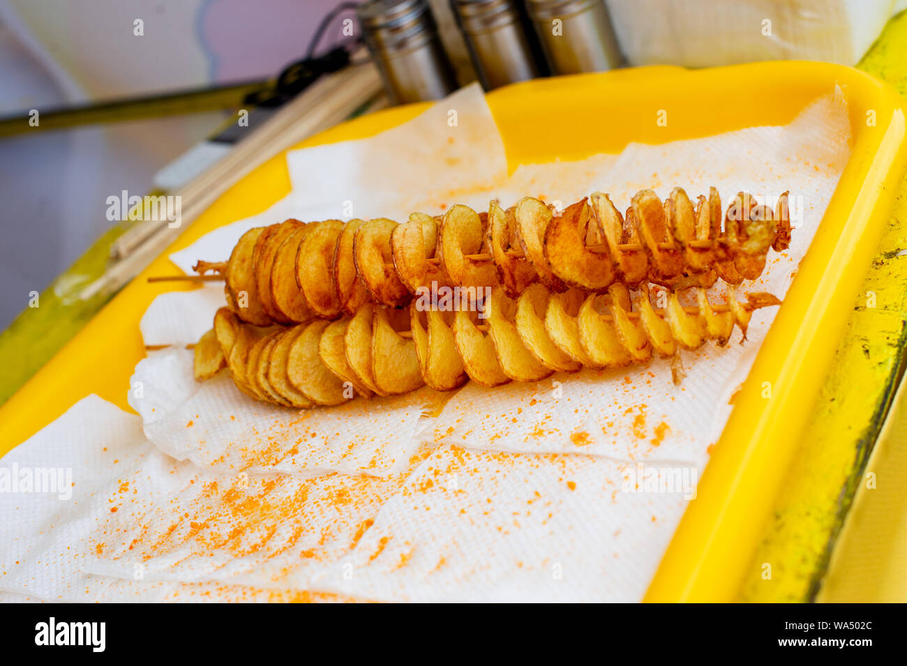 Espiral de papas fritas, en palos de madera, en espiral. Venta de alimentos  en el mercado. Insalubres alimentos fritos. Alimentos en la calle, en una  espiral de papa fritos en un palo.