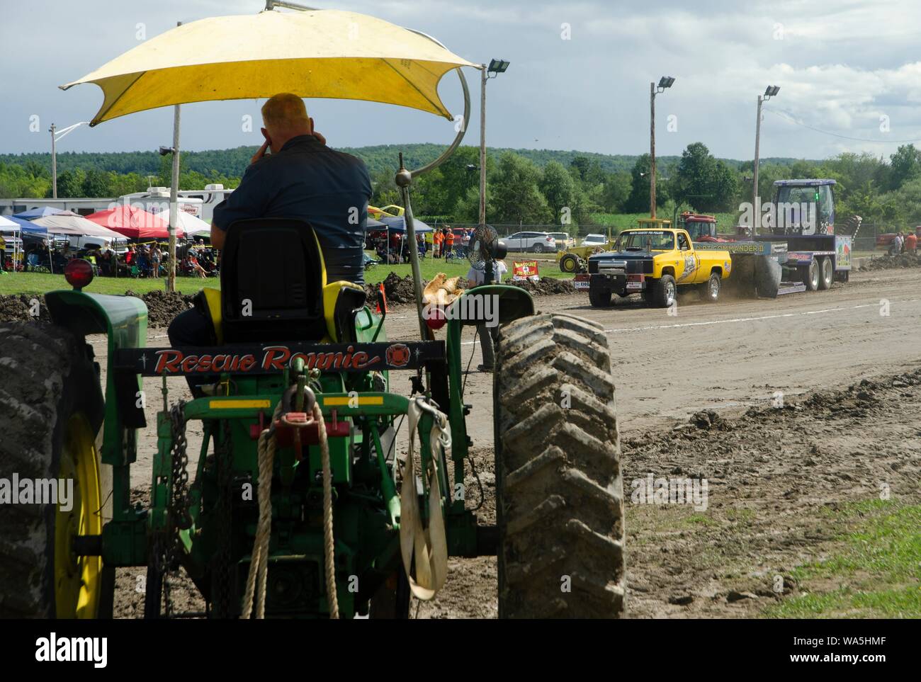 Un hombre se sienta en un tractor como él ve a un camión tire en la Feria del Condado de Addison en New Haven, Vermont, EE.UU. Foto de stock