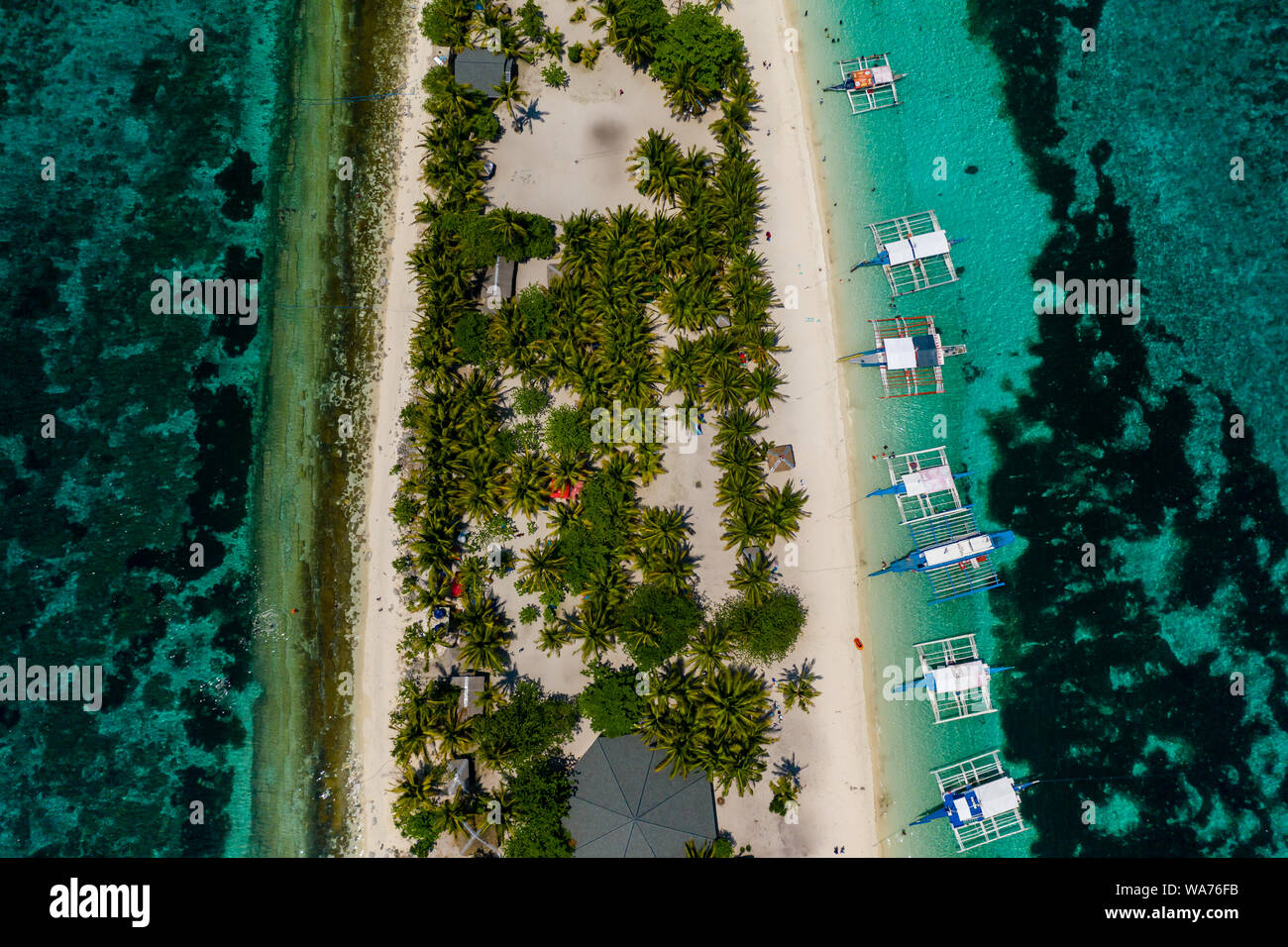 Antena drone vista de banca tradicional barcos amarrados junto a una pequeña isla tropical, rodeada por arrecifes de coral (Isla Kalanggaman) Foto de stock