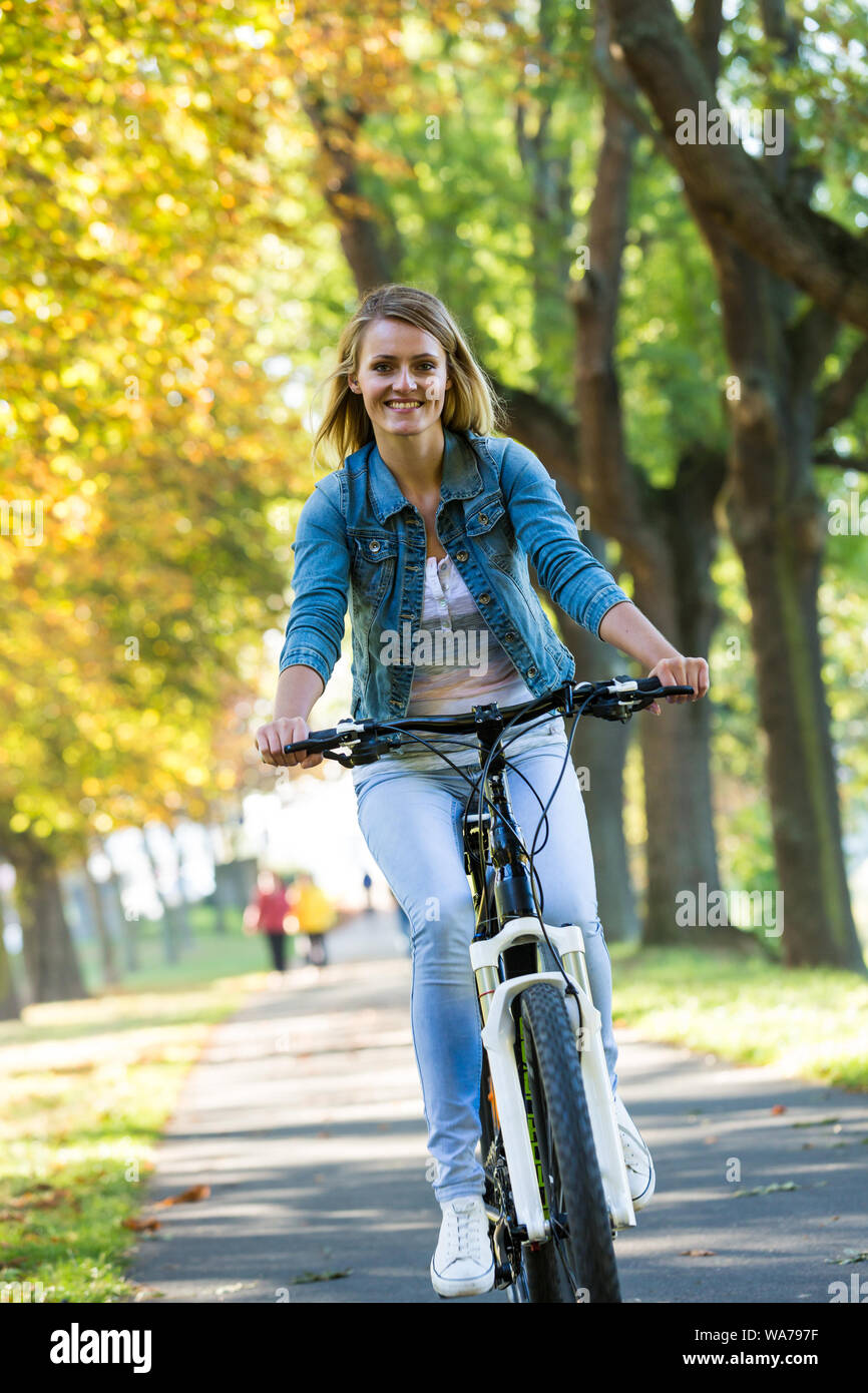 Concepto De Estilo De Vida Activo De Otoño ,. Chica Casual Deportiva Mujer  Joven Relajante En El Parque Otoñal Con Bicicleta, Al Aire Libre Fotos,  retratos, imágenes y fotografía de archivo libres