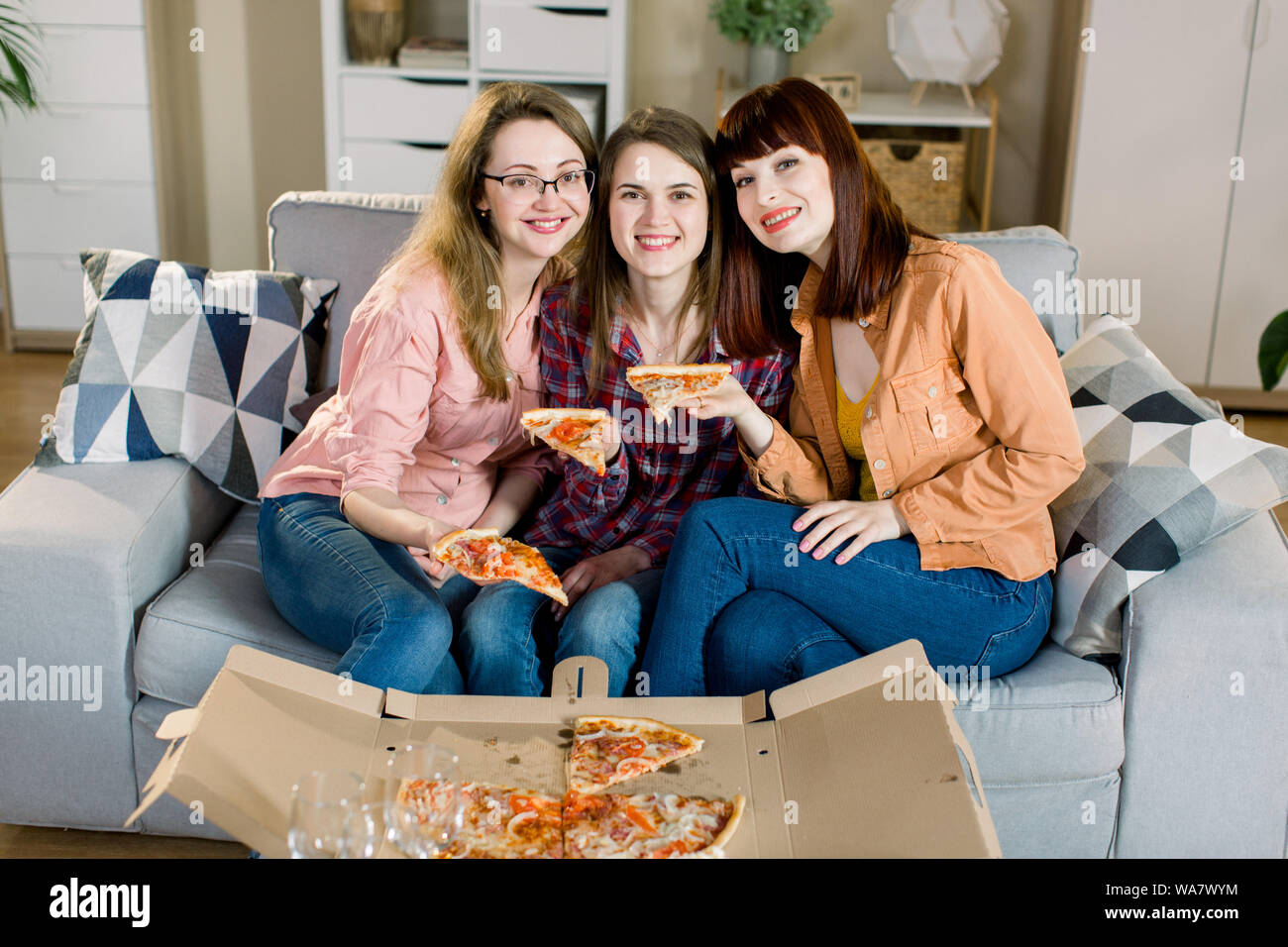 Retrato de tres amigas jóvenes felices en ropa casual de comer pizza en el  sofá en casa. La mujer amistad, comer juntos Fotografía de stock - Alamy