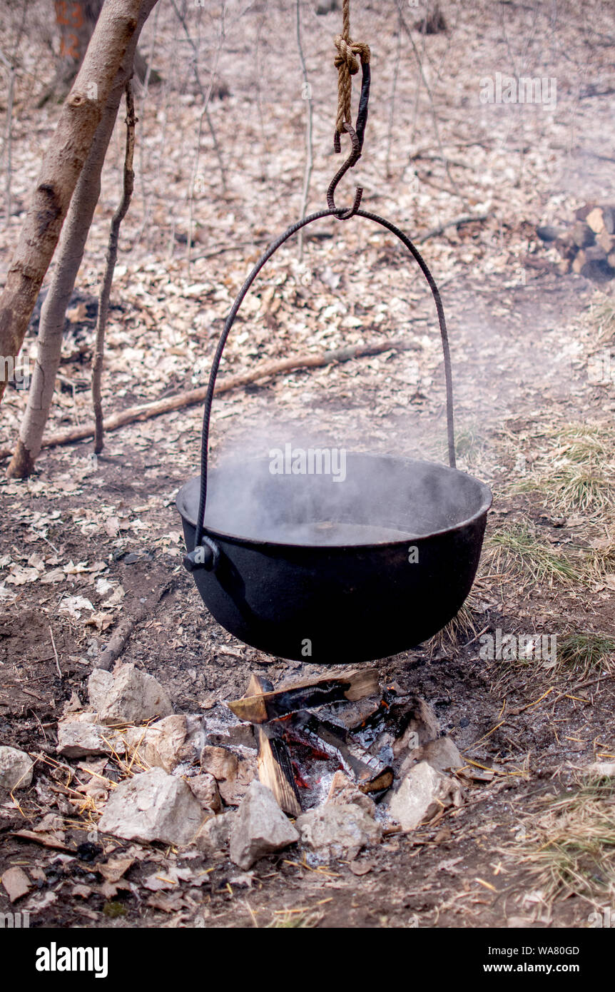 Una olla de hierro fundido suspendida sobre un fuego caliente, boil off arce fresca en sap pegajoso dulce de azúcar y jarabe de arce Foto de stock