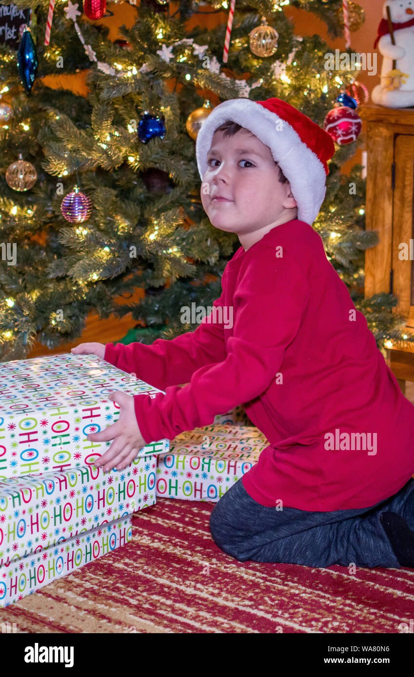 Little Boy es capturado tratando de abrir los regalos de Navidad Foto de stock
