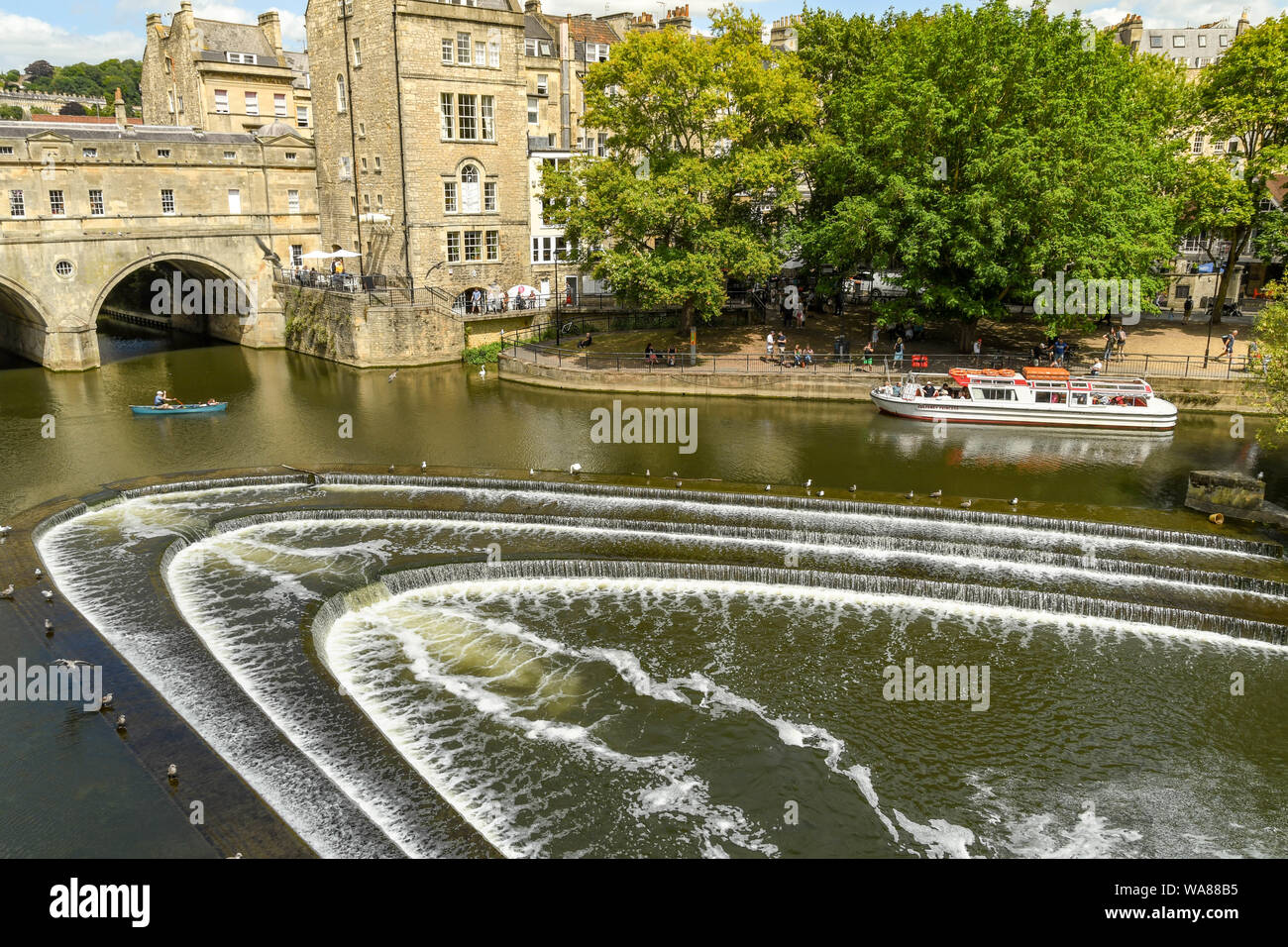 BATH, Inglaterra - Julio 2019: el azud Pulteney con forma de herradura, sobre el río Avon y el puente Pulteney en el centro de Bath. Foto de stock