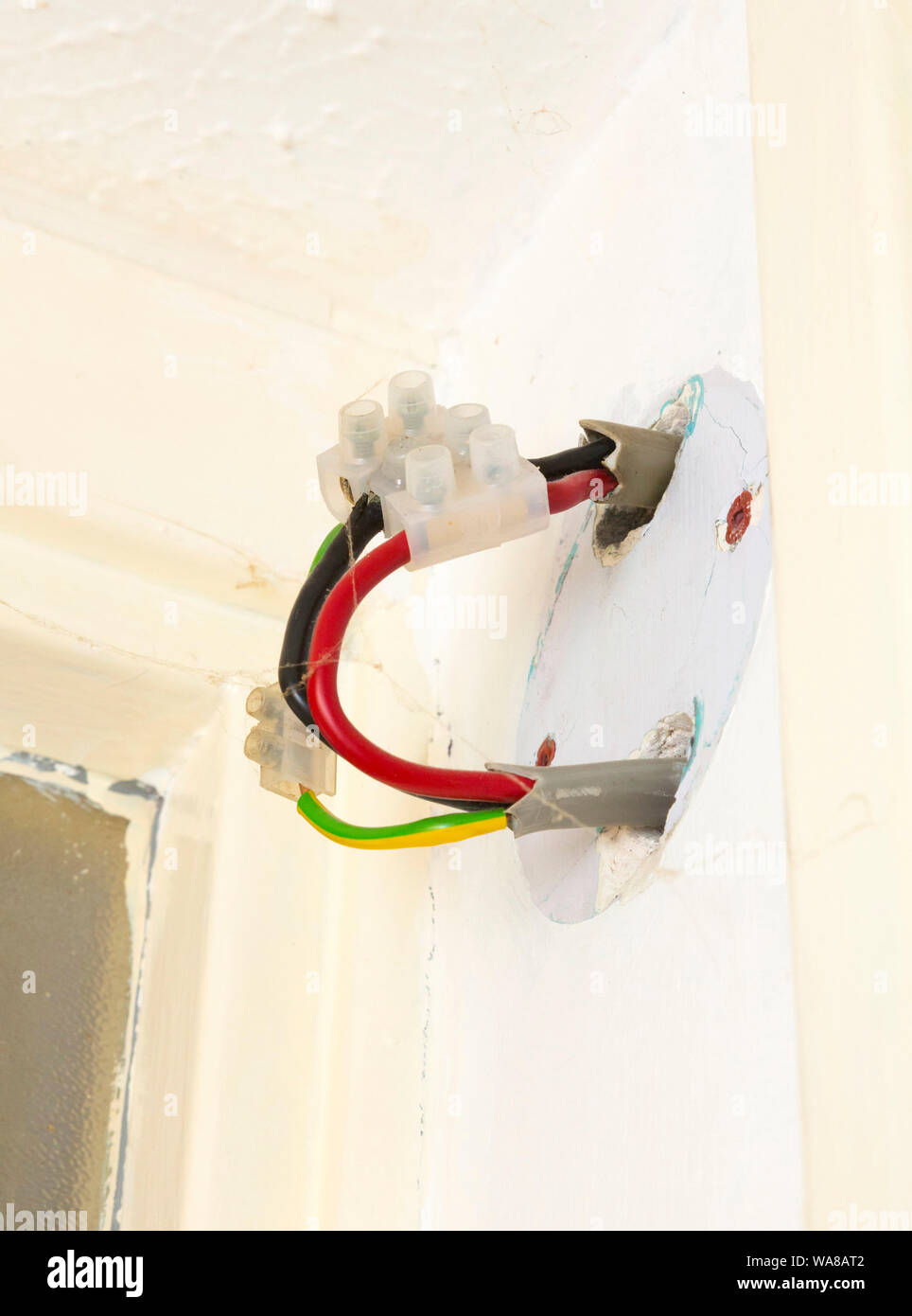 Peligrosa conexión eléctricos expuestos en la pared interior home Foto de stock