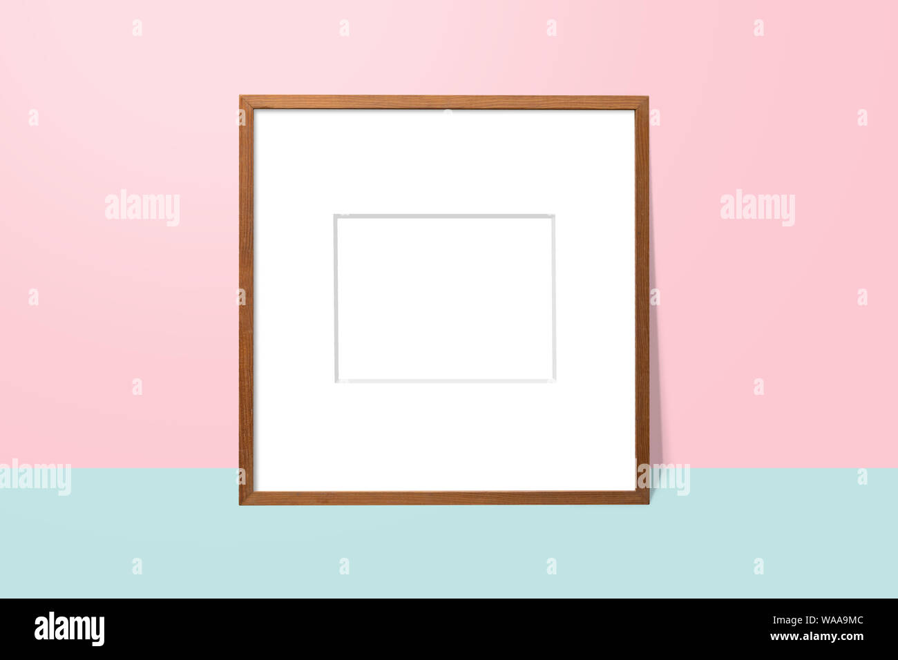 Espacio en blanco vacío de madera bastidor en blanco y rosa con inclinada contra la pared y el piso azul. un simple marco de fotos en blanco para su presentación o decorar backgroun Foto de stock