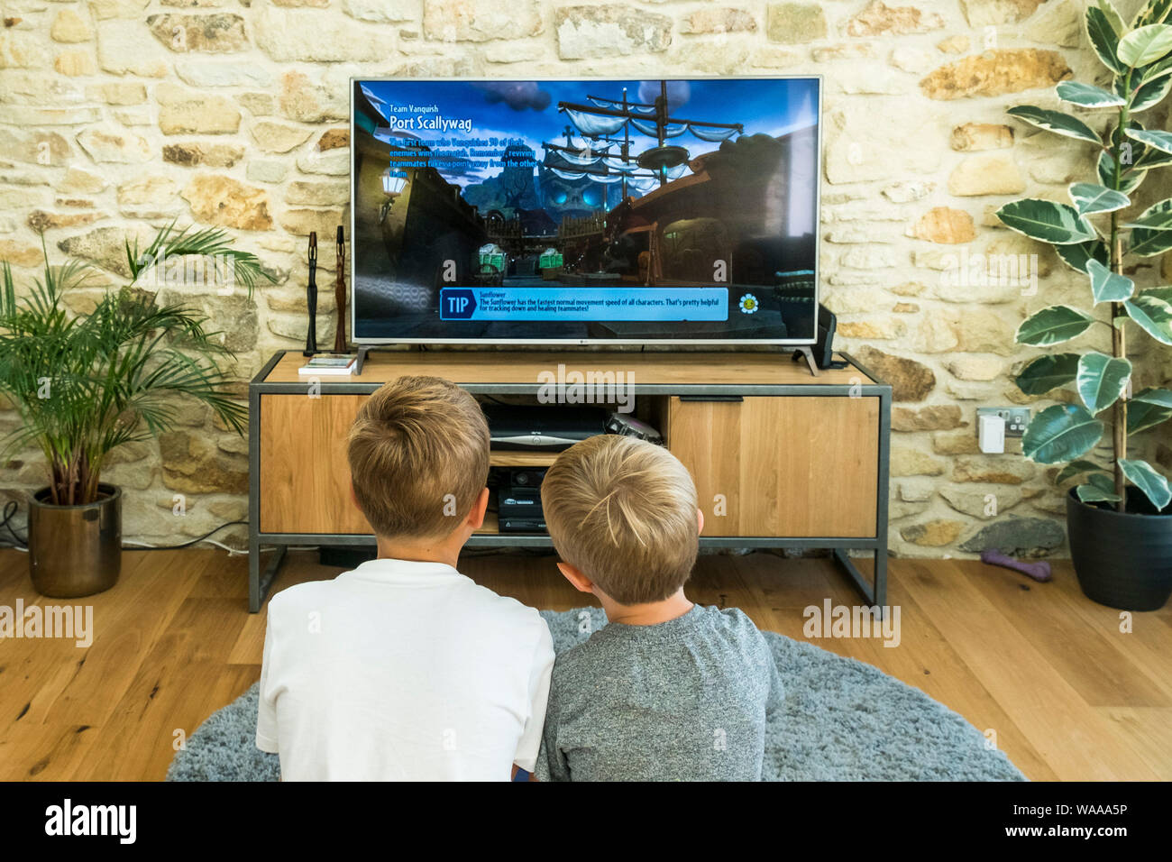 Dos jóvenes muchachos jugando un juego de video en una pantalla grande. Foto de stock