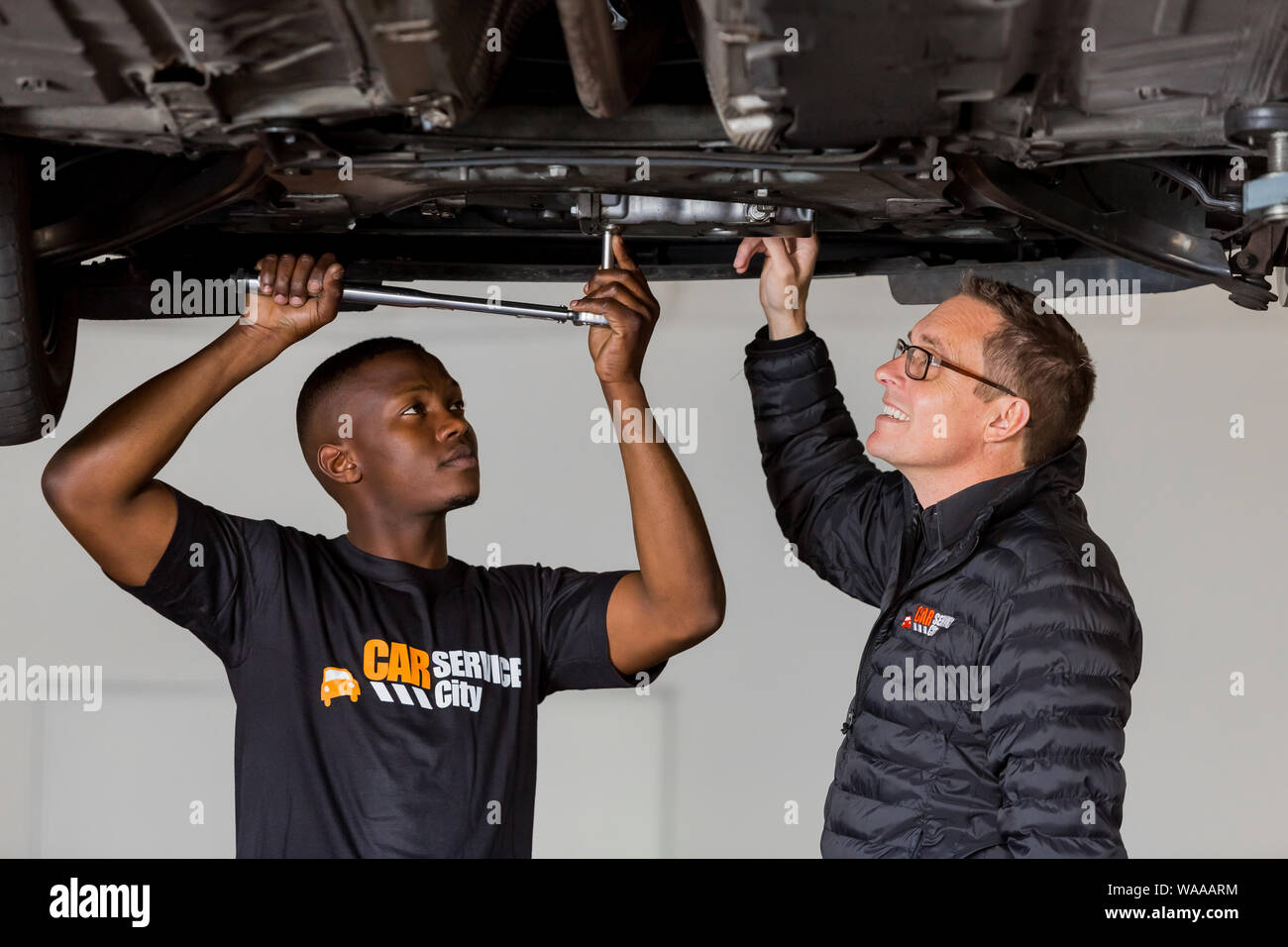 Vista parcial de la mecánica automotriz en uniforme usando guantes  protectores al taller de reparación de automóviles Fotografía de stock -  Alamy