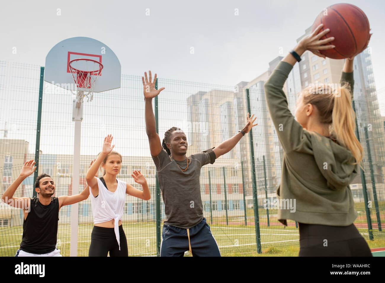 Grupo de estudiantes interculturales o amigos en sportswear jugando baloncesto Foto de stock