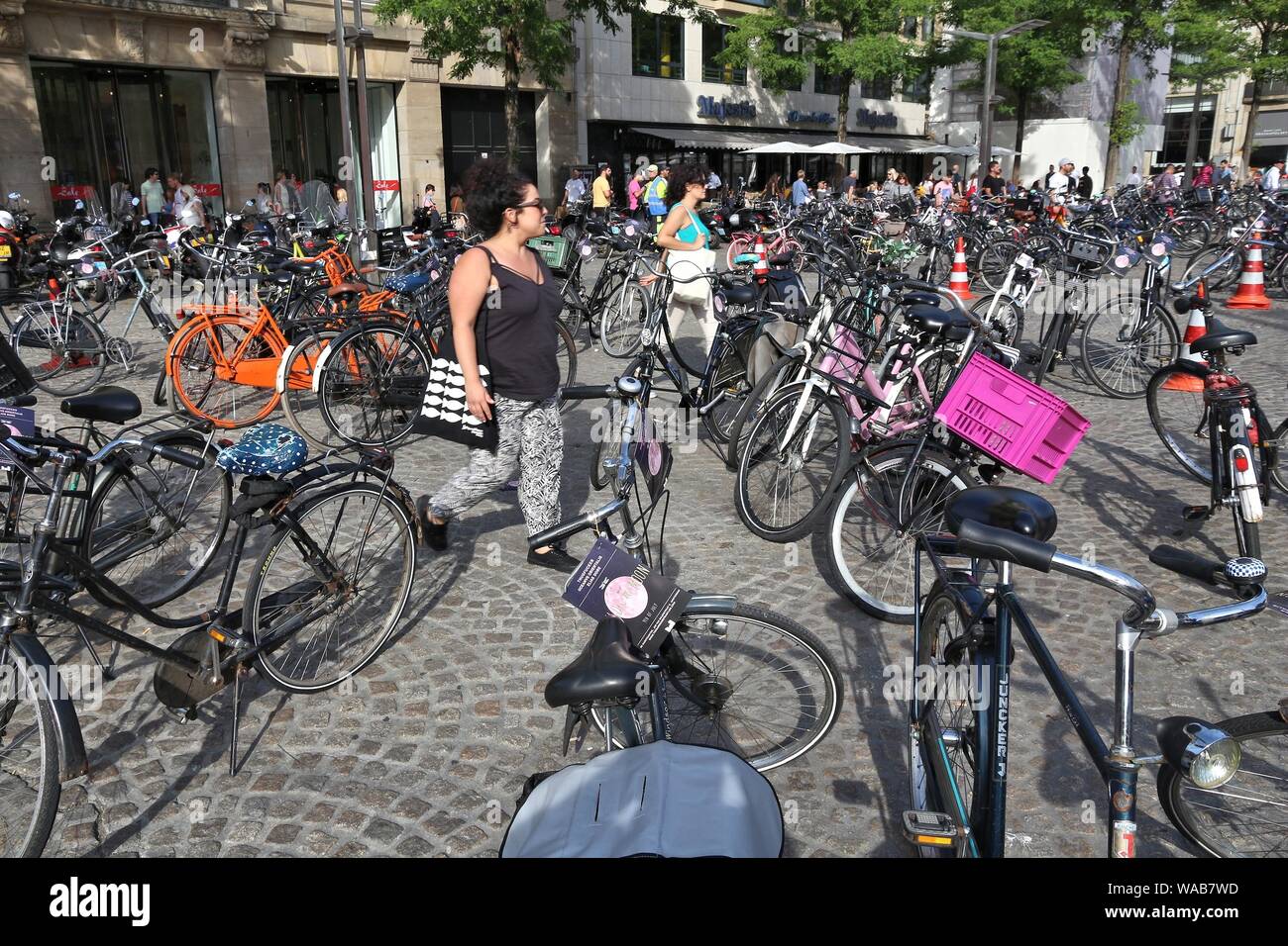 AMSTERDAM, Holanda - Julio 9, 2017: la gente camina a través de aparcamiento de bicicletas en la Plaza Dam en Amsterdam, Países Bajos. Ámsterdam es la ciudad capital de T Foto de stock