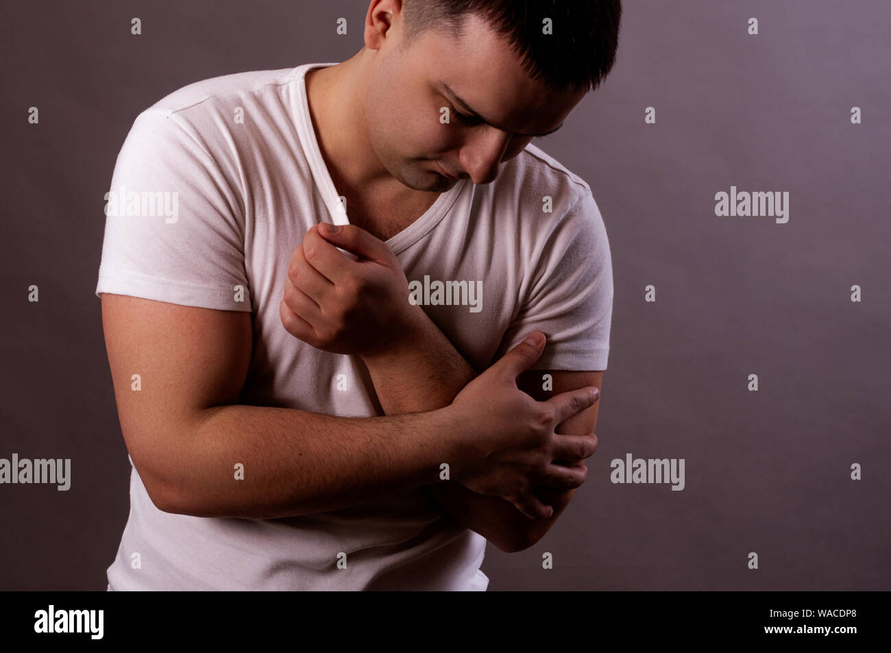 Dolor en la mano. Un hombre joven en una camiseta blanca la mano Foto de stock
