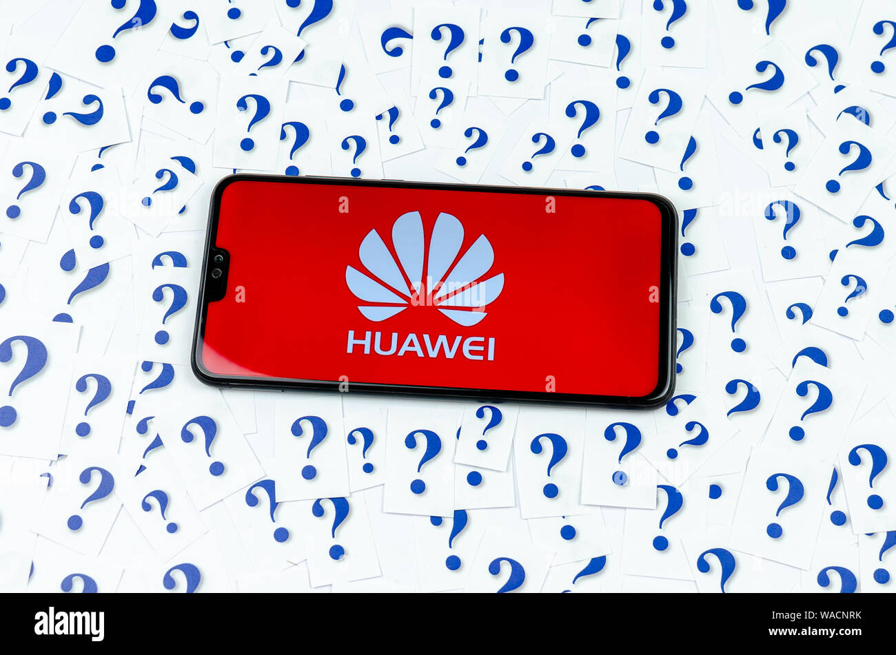 En el logotipo de HUAWEI HUAWEI smartphone y un montón de papel signos de interrogación alrededor. La fotografía conceptual acerca del futuro de la tecnología en los EE.UU. gigante. Foto de stock