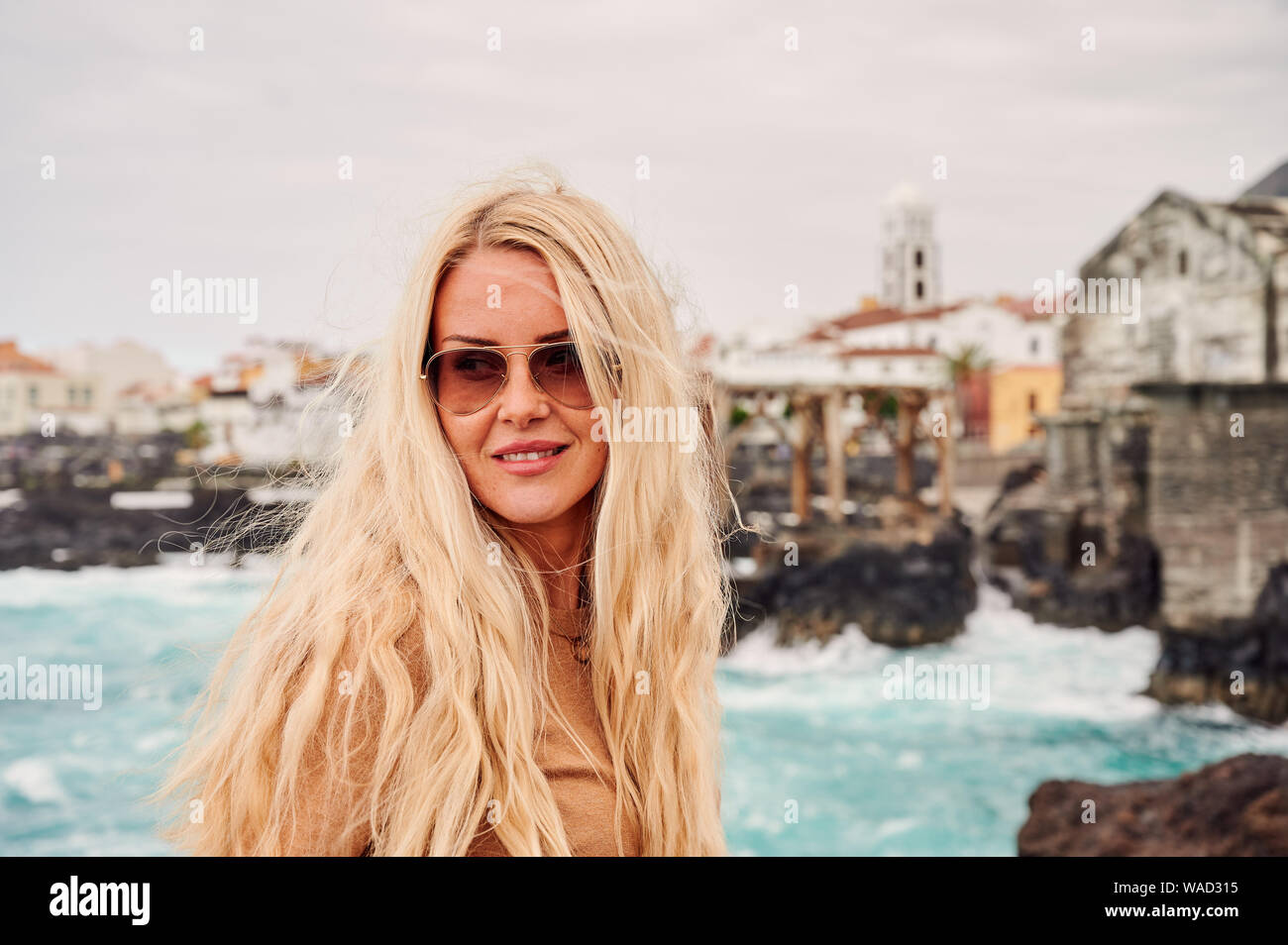 Inspirado en la mujer rubia, gafas de sol y con la habilidad de volar lejos  de pelo sonriente antecedentes de orilla rocosa de Tenerife, España  Fotografía de stock - Alamy