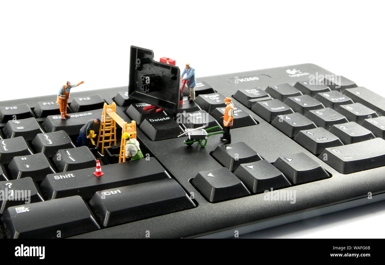 Pocas figuras mundiales reparar el teclado del ordenador o intenten  piratear o intergate en el sistema Fotografía de stock - Alamy