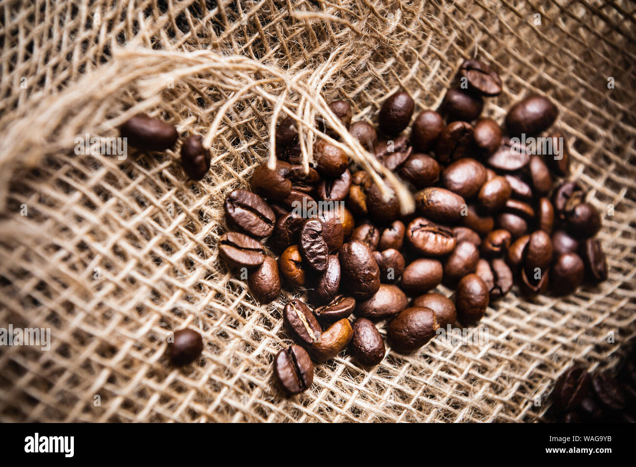 Salpicados de café tostado en grano en arpillera Foto de stock