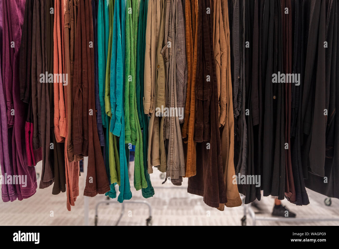 Fila de tonos color tierra tejido jeans o pantalones de mezclilla y  pantalones colgando en el colgador. Segunda mano estilo retro de tonos  oscuros pantalones se venden en la tienda outlet Fotografía