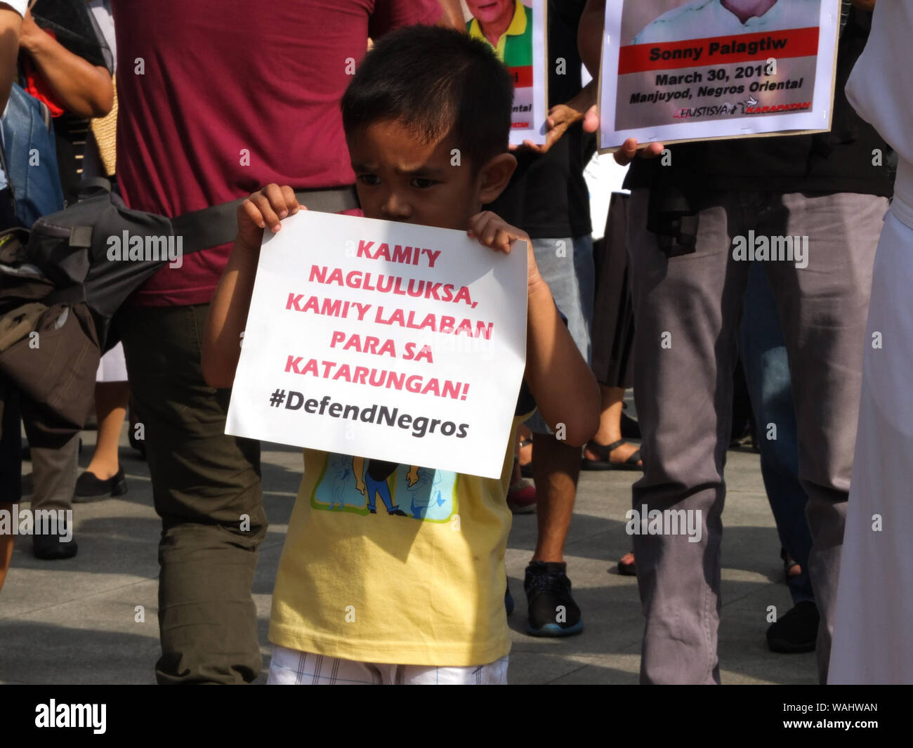 Un niño sostiene una pancarta durante la manifestación.La familia del asesinado víctimas de presuntas ejecuciones sumarias en la provincia de Negros organizaron una manifestación de protesta en Liwasang Bonifacio en Manila durante el día de duelo nacional y solidaridad para poner fin a las matanzas en la región. Foto de stock