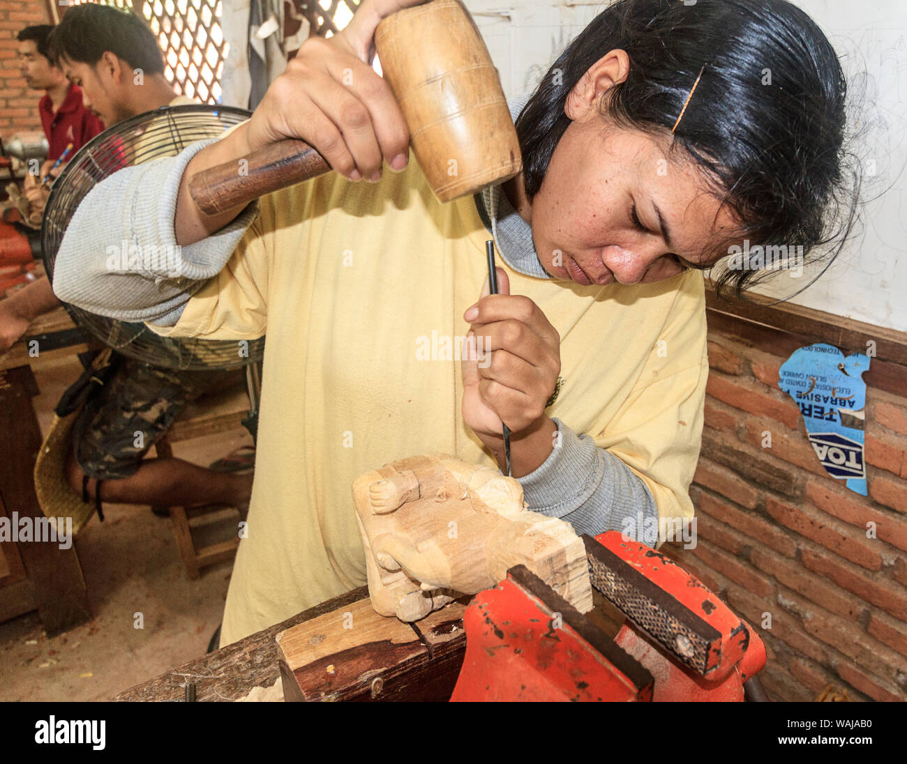 En Siem Reap, Camboya. Mujer joven tallando una figura de madera a los artesanos de Angkor, un taller en el que se capacita a jóvenes incultos y discapacitados jóvenes camboyanos en la artesanía. (Uso Editorial solamente) Foto de stock