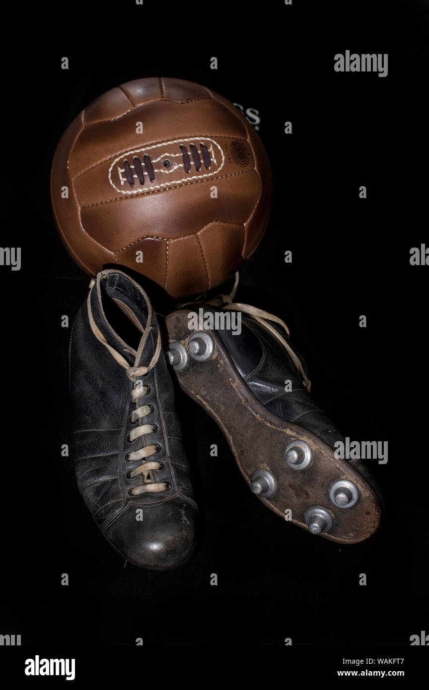 Balón de fútbol de cuero antiguo y vintage los tacos, botas, zapatos de  fútbol contra un fondo negro Fotografía de stock - Alamy