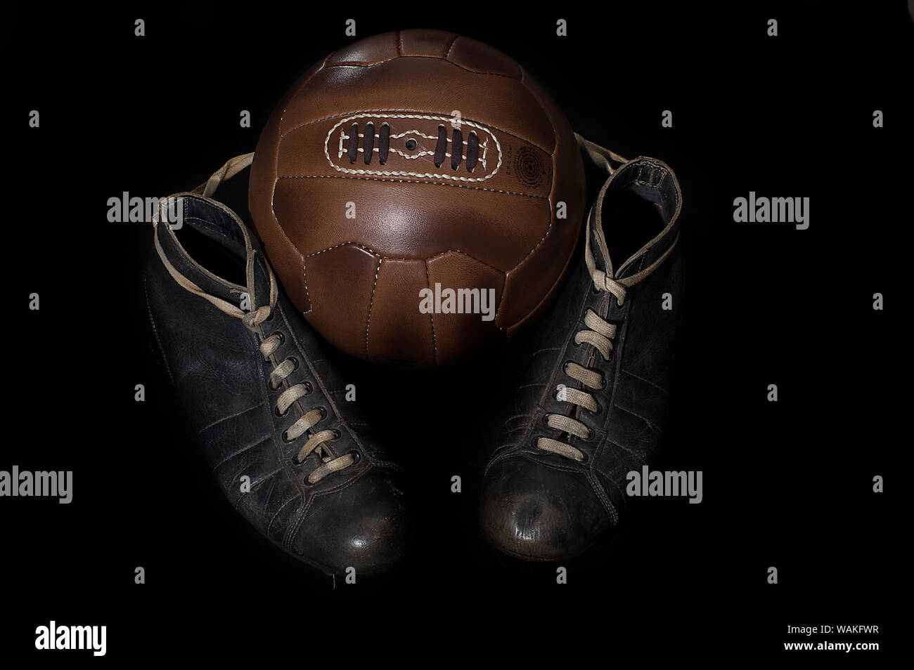 Balón de fútbol de cuero antiguo y vintage los tacos, botas, zapatos de  fútbol contra un fondo negro Fotografía de stock - Alamy