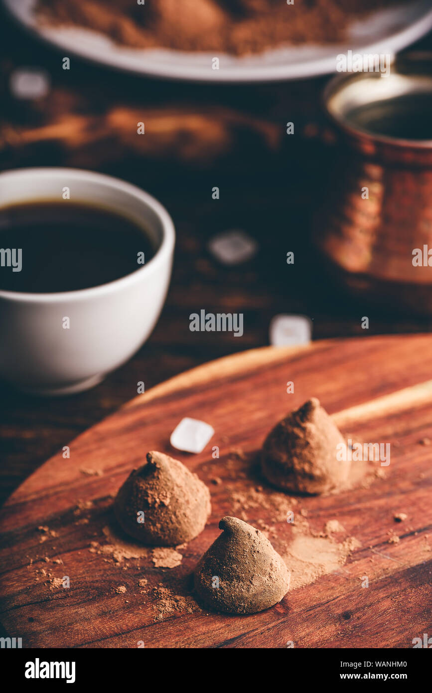 Trufas de chocolate caseras recubiertos de cacao en polvo con café negro Foto de stock