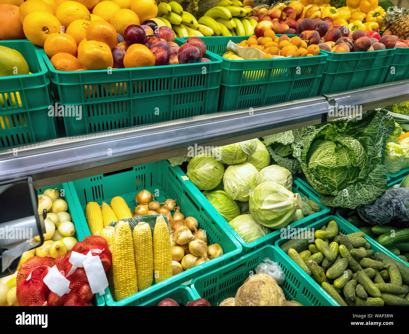 Verdulero con estantes llenos de frutas y verduras Foto de stock