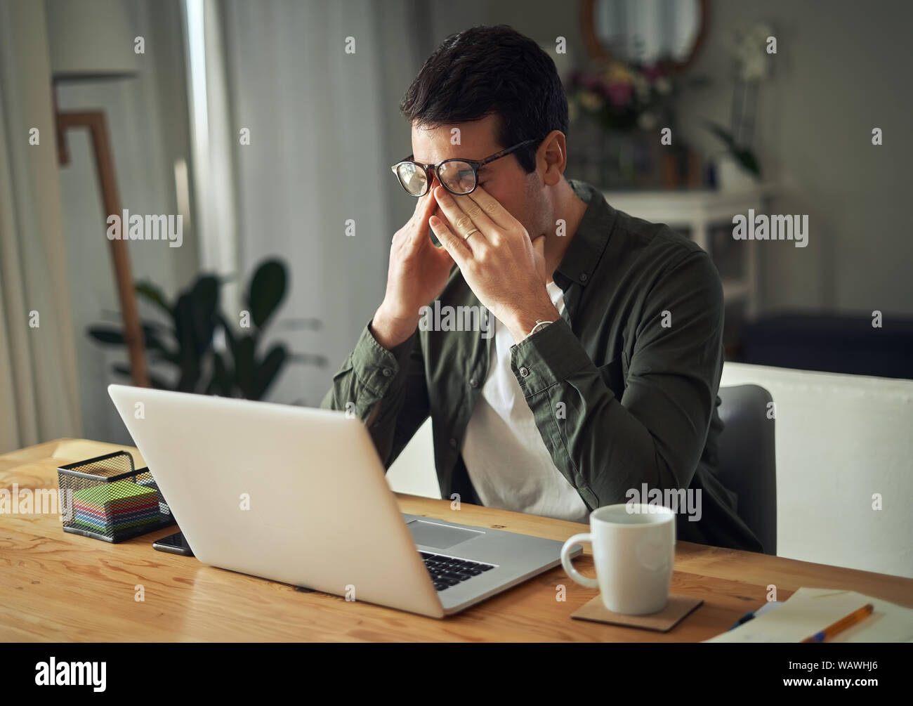 Hombre teniendo tiempo estresante trabajando en el portátil en casa Foto de stock
