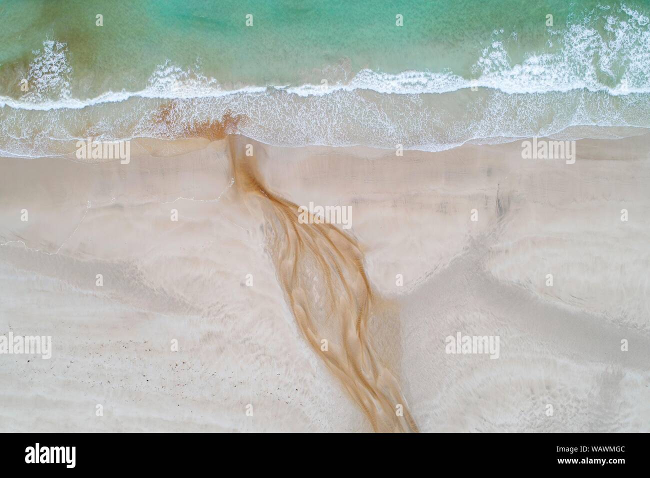 Arroyo con agua ferruginosa rojiza fluye a lo largo de una playa de arena en el mar, cerca de Stornoway, la isla de Lewis y Harris, Escocia, Gran Bretaña, Gran Foto de stock
