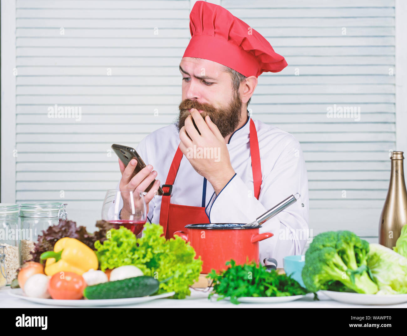 Hombre chef buscar en internet receta cocinar los alimentos. Chef ver  smartphone show culinario. Una escuela culinaria. Hipster en hat y delantal  aprendiendo cómo cocinar en línea. Educación Culinaria en línea. Concepto