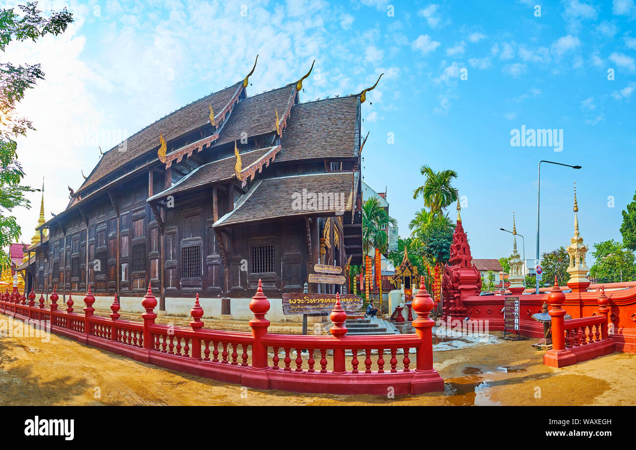 CHIANG MAI, Tailandia - Mayo 2, 2019: Panorama medieval viharn teca de Wat Phan Tao con pyathat multitired (techo), chofa decoraciones y un cerco rojo Foto de stock