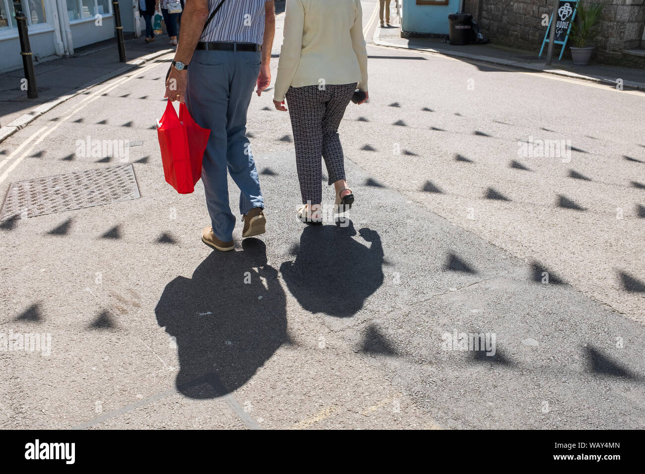 Dos personas que proyectan sombras mientras compras en Falmouth, Cornualles, en el REINO UNIDO Foto de stock