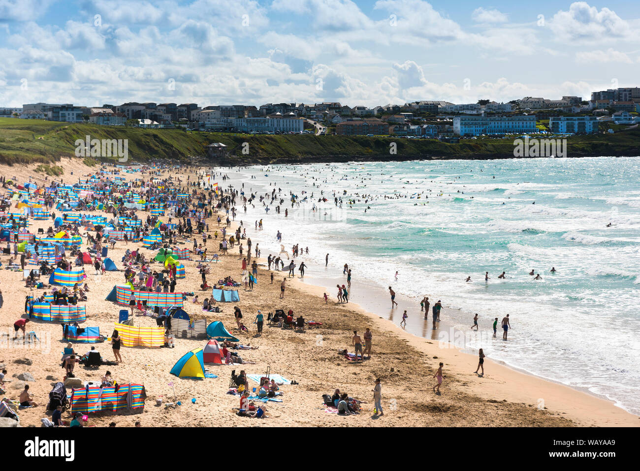 Turistas en vacaciones en una estaycation en una soleada playa de Fistral en Newquay en Cornwall. Foto de stock