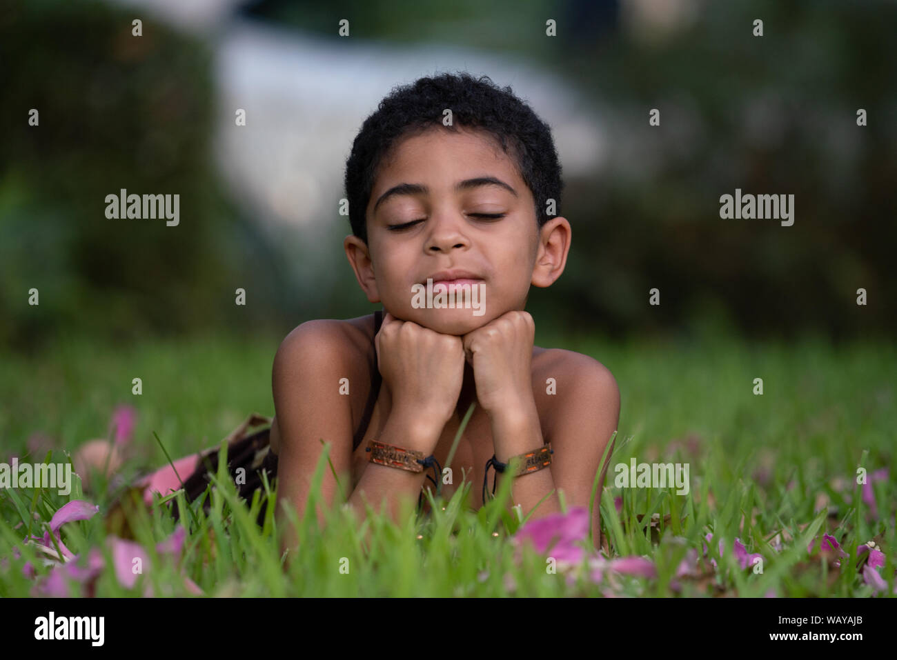 Retrato de una joven muchacha de raza mixta con los ojos cerrados descansando sobre el césped Foto de stock
