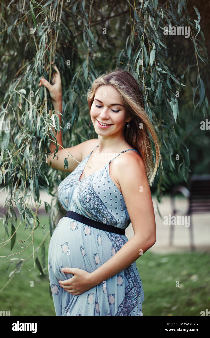 Desierto productos quimicos Contador Feliz saludables durante el embarazo y la maternidad. Retrato de mujer  caucásica joven embarazada vestidos de largo vestido azul posando en el  parque afuera. Hermosa pensive fe Fotografía de stock - Alamy