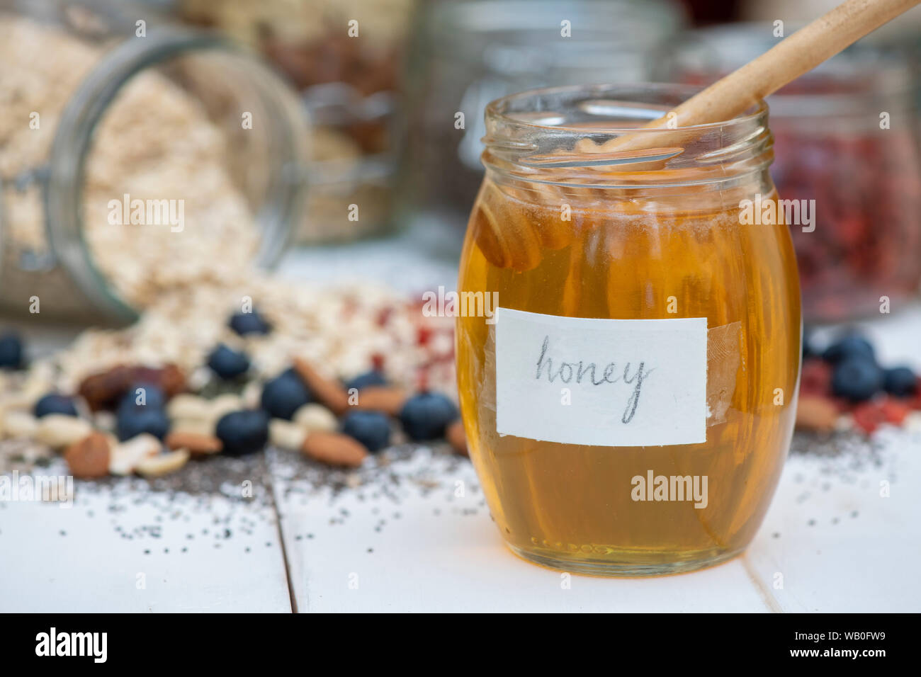 Tarro de miel con frutos, nueces, semillas y avena Foto de stock