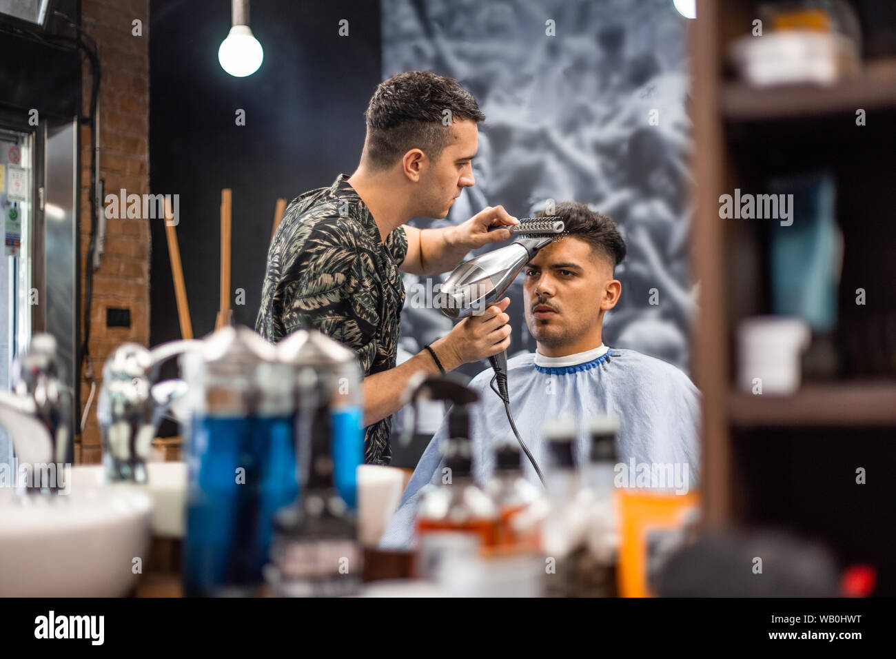 Close-up, master Barber ¿el peinado de estilismo y seca el cabello con secador, a Guy. Concepto de peluquería. Soft Focus. Foto de stock
